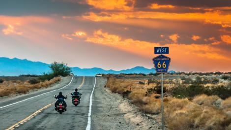 Motorcycles cruising through the California desert on Route 66 at sunset