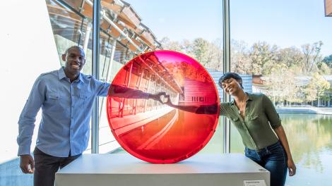 A couple posing with "Big Red Lens" by Frederick Eversley at Crystal Bridges Museum of American Art in Bentonville, Arkansas