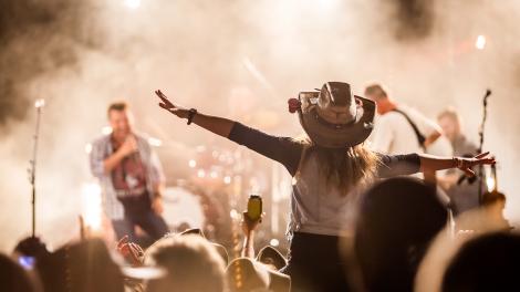 Dancing and singing along with the performers at a country music festival Dancing and singing along with the performers at a country music festival