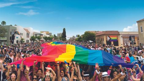 Participants kicking off the San Diego Pride parade with a large rainbow flag