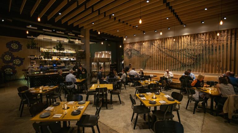 在 Maypop 餐廳內路易斯安那州與越南壁畫背景下用餐