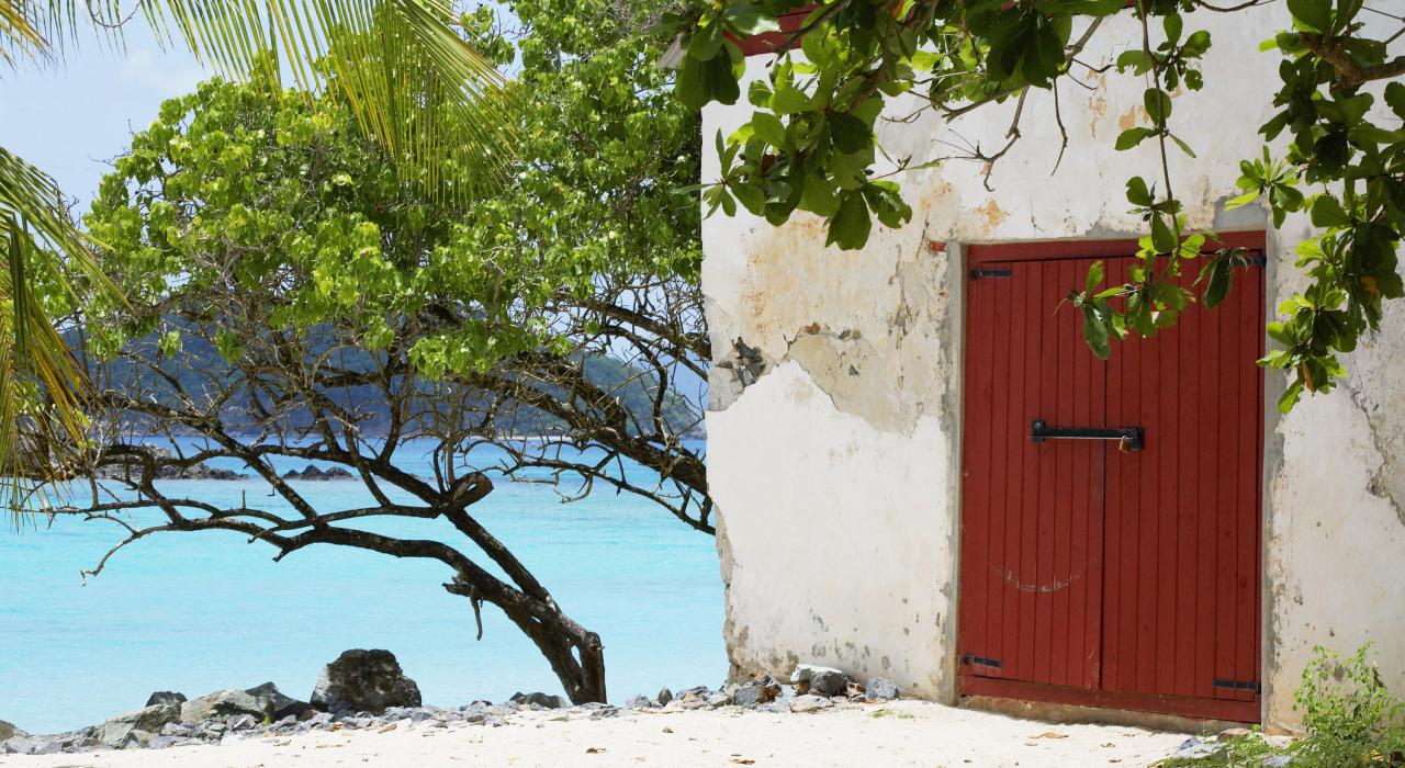 A lone house sits next to the crystal blue sea