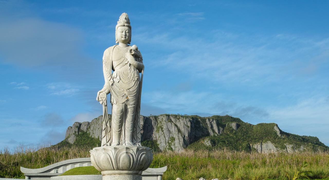 萬歲崖紀念園區中的日式佛像，背景為自殺崖