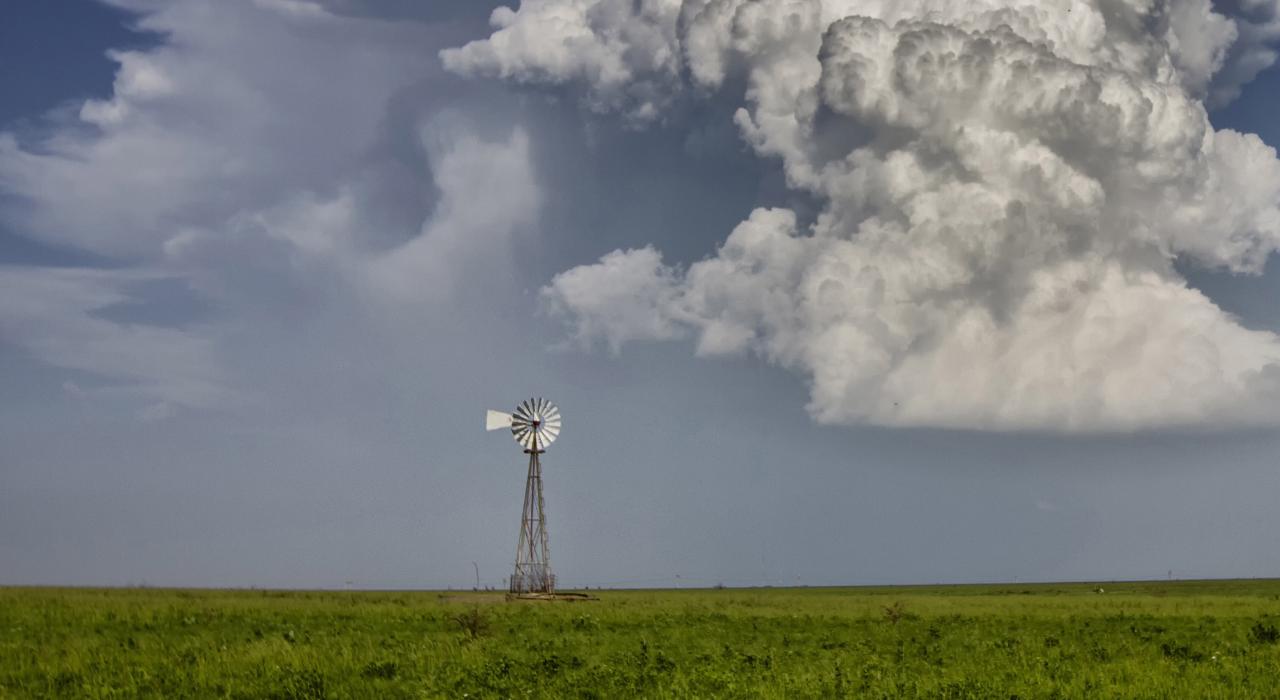 軟綿雲朵堆疊在農場上孤單風車的後方