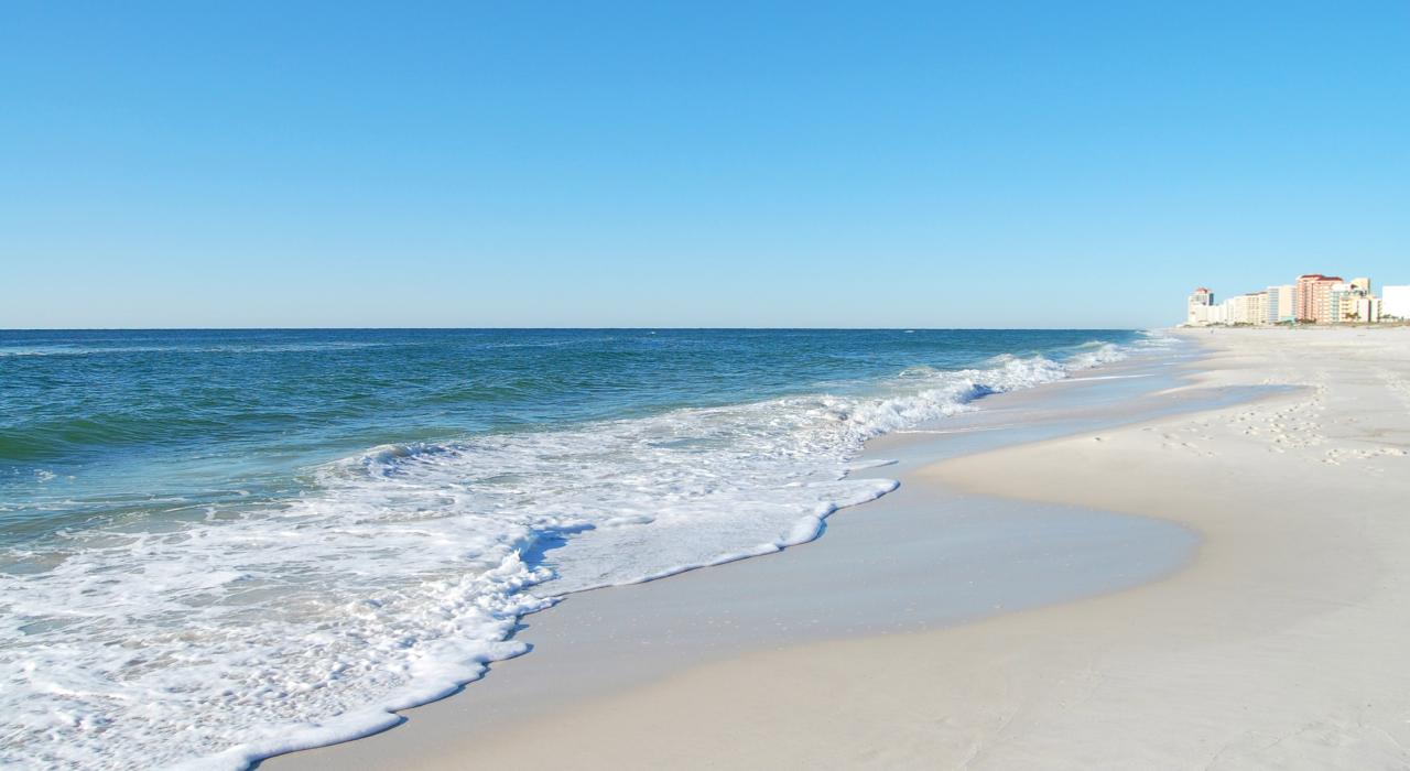 Waves rolling in over the wide, white-sand beach