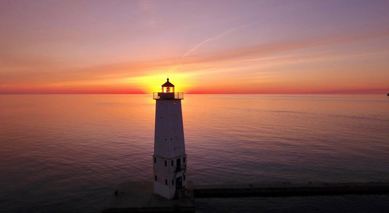 The sun setting over Lake Michigan behind the Frankfort Lighthouse The sun setting over Lake Michigan behind the Frankfort Lighthouse